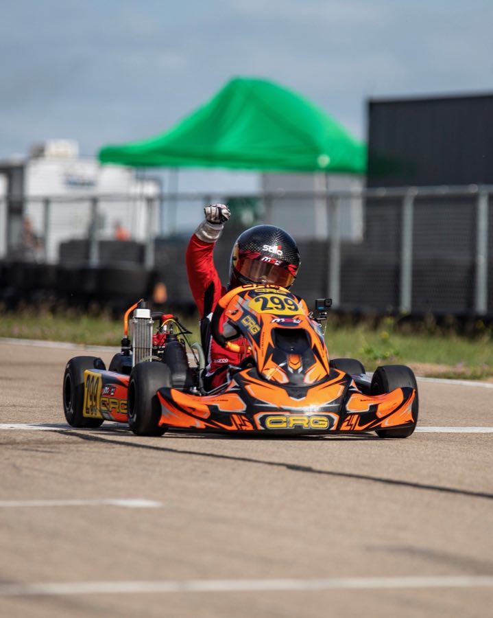 J.J. crossing the finish line in kart number 299 with one fist raised.